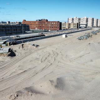 A view of a sandy area near urban buildings, possibly indicating ongoing construction or development.
