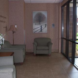 A cozy lobby area with armchairs, a sofa, a lamp, and a painting on the wall.