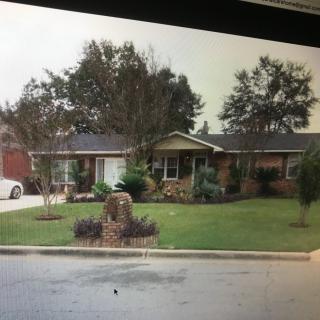 A suburban house with a well-maintained lawn and trees in the front yard.
