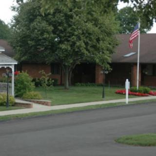 A suburban house with a well-maintained lawn, an American flag, and a garden.
