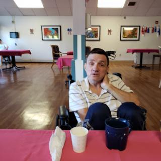 A person seated in a wheelchair at a dining table, set in a cozy indoor environment.