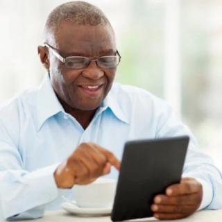 A smiling man using a tablet indoors.