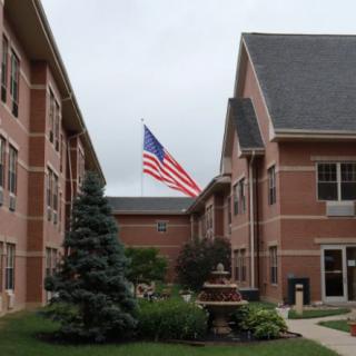 A view of a brick building with an American flag in the courtyard.
