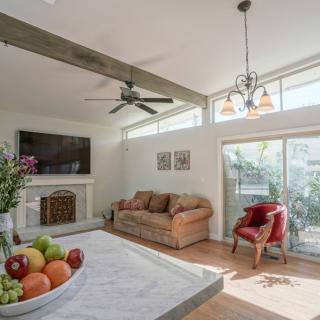 A modern living room with a comfortable sofa, fireplace, and a large TV. Natural light flows through the windows, illuminating the space.
