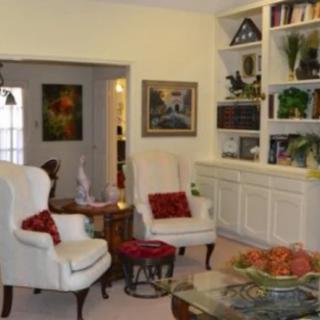 A cozy living room with armchairs, a bookshelf, and decorative art.