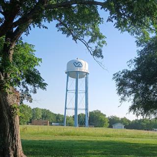 A serene view of a water tower amidst lush greenery under a clear blue sky.