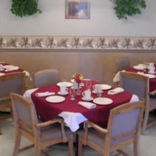 A neatly arranged dining area with tables set for guests, featuring red tablecloths and elegant place settings.
