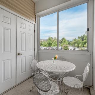 A cozy dining nook featuring a white table and chairs, illuminated by natural light from the large window.