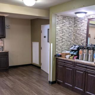 A modern kitchen area featuring a coffee station with wooden cabinets and flooring.