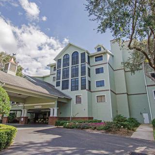 A large hotel building with a modern design, surrounded by trees and under a partly cloudy sky.