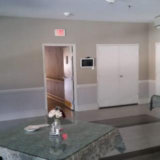 An interior view featuring a hallway with an exit sign, a table adorned with flowers, and carpeted flooring.