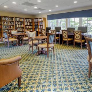 A cozy library room with bookshelves, computers, and seating areas for reading.