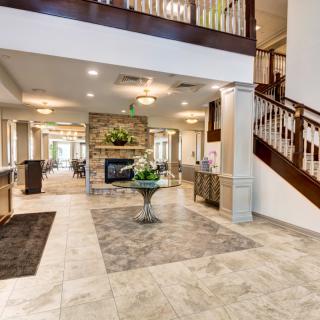 A spacious and elegantly decorated lobby with a central fireplace, staircase, and welcoming decor.