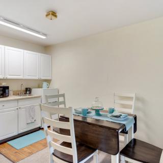 A modern kitchen and dining area with white cabinets and a neatly set dining table.