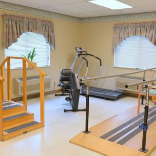 A rehabilitation room equipped with exercise equipment and parallel bars for physical therapy.
