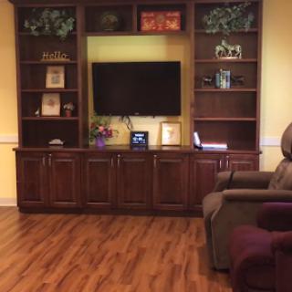 A cozy living room setup featuring a wooden TV cabinet with shelves, a television, and comfortable seating.