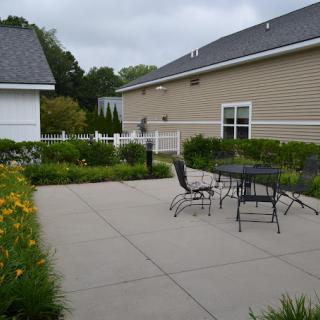 A peaceful patio with outdoor furniture surrounded by lush garden landscaping.