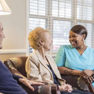 A caregiver engaging in a friendly conversation with elderly residents in a nursing home.