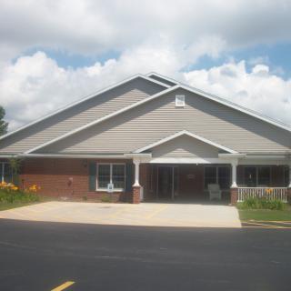 A view of a commercial building exterior with a parking area in front and a cloudy sky above.