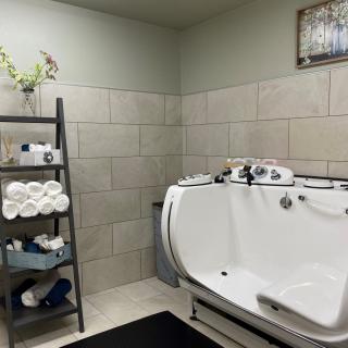 A modern bathroom featuring a sleek bathtub, neatly arranged towels on a shelf, and stylish tile walls.