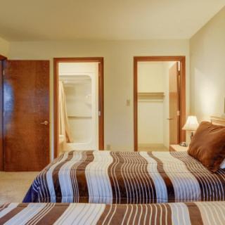 A cozy bedroom with a striped bedspread and warm lighting.