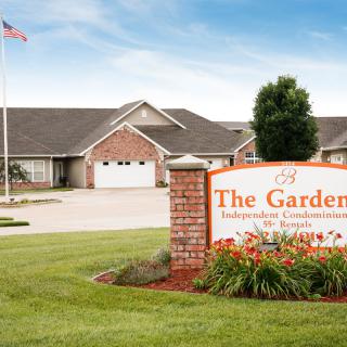 Entrance sign of The Gardens, a retirement community with well-maintained lawns.