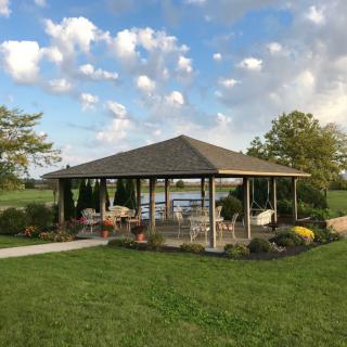 A serene outdoor pavilion surrounded by lush greenery and an expansive sky.