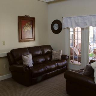 A cozy living room with brown leather sofas, wall art, and a large window.