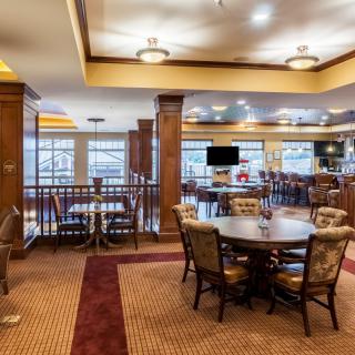 A cozy restaurant interior with tables, chairs, and a bar area.