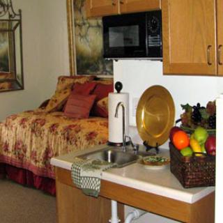 A cozy kitchen and bedroom space featuring a fruit bowl and a microwave.
