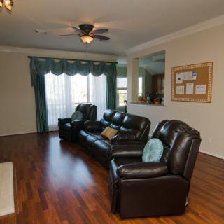 A cozy living room with leather sofas, wood flooring, and a ceiling fan.