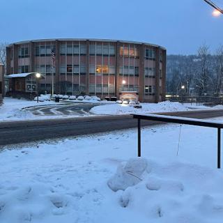 A snow-covered scene featuring a circular building illuminated in the evening light.