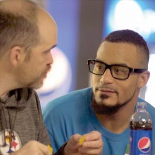 Two men having a conversation while enjoying snacks and a beverage.