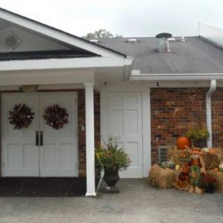 A front porch decorated for autumn with wreaths, pumpkins, and hay bales.