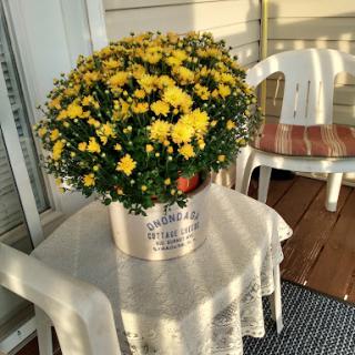 A vibrant pot of yellow flowers brings a cheerful touch to the porch table.
