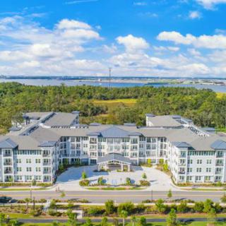 Aerial view of a modern residential complex surrounded by greenery and a blue sky backdrop.