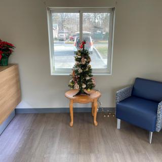 A cozy corner featuring a small Christmas tree and a comfortable chair by the window.