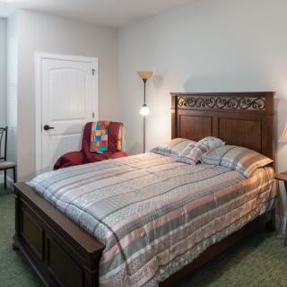 A cozy bedroom with a wooden bed, striped bedding, and a floor lamp beside it.