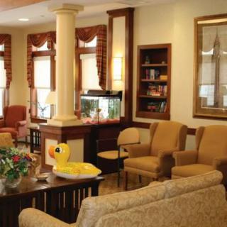 A cozy living room with comfortable seating, a fish tank, and natural light streaming in.