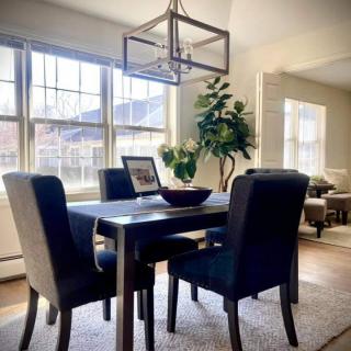 A modern dining room with a stylish table set, abundant natural light, and green indoor plants.