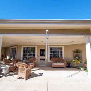 A sunny patio with wicker furniture and decorative plants under a clear blue sky.