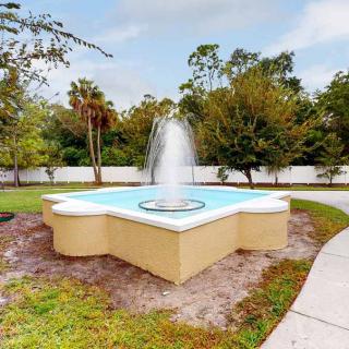 A decorative outdoor fountain surrounded by trees and a pathway in a garden setting.
