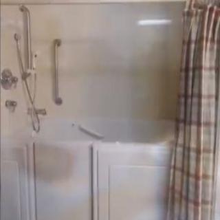 A bathroom shower area with a plaid curtain and safety grab bar.