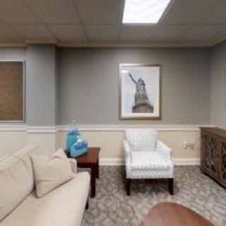 A cozy living room featuring a sofa, armchair, and artwork on the wall.