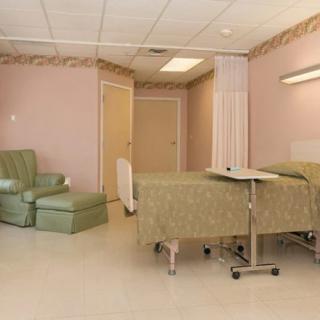 A hospital room with a bed and a comfortable chair for patients.