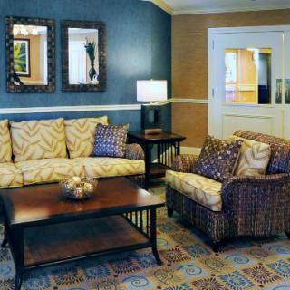 A cozy living room with a sofa, armchair, and coffee table, featuring stylish decor and lighting.