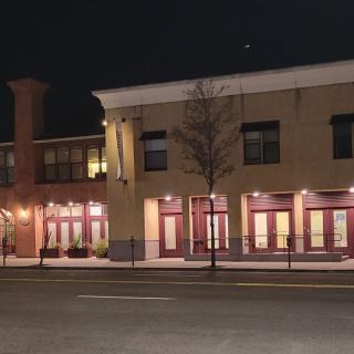 A street view of buildings with illuminated windows at night.