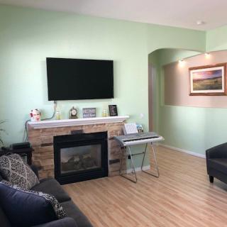 A cozy living room with a modern fireplace, wall-mounted TV, and comfortable seating.