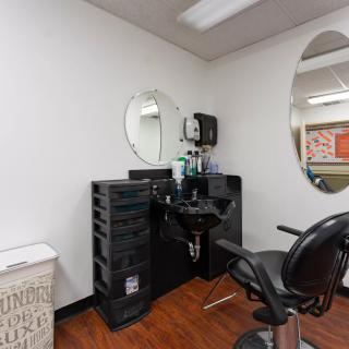 A modern hair salon setup featuring a styling station with mirrors, a salon chair, and various hairstyling tools.