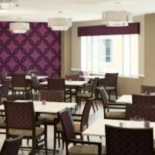 A modern restaurant dining area featuring tables and chairs with purple accent walls and chandeliers.